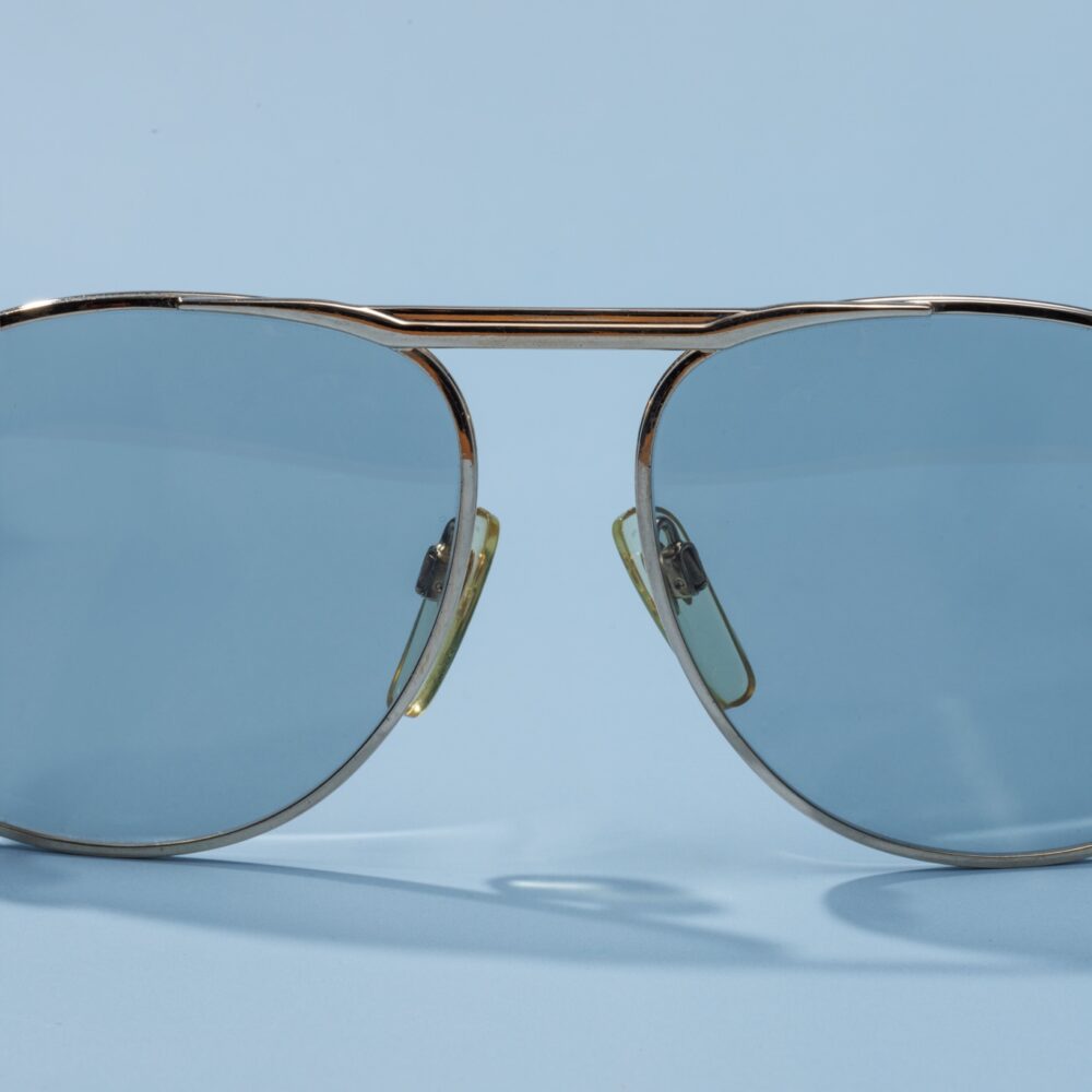 Lunettes de soleil vintage des années 80 de la marque Metzler. Monture en acier doré fabriquée main en Allemagne d'un savoir-faire lunetier authentique, avec des verres bleus fantastiques. Les lunettes Metzler sont toutes fabriquées à la main, avec des matériaux soigneusement choisis.